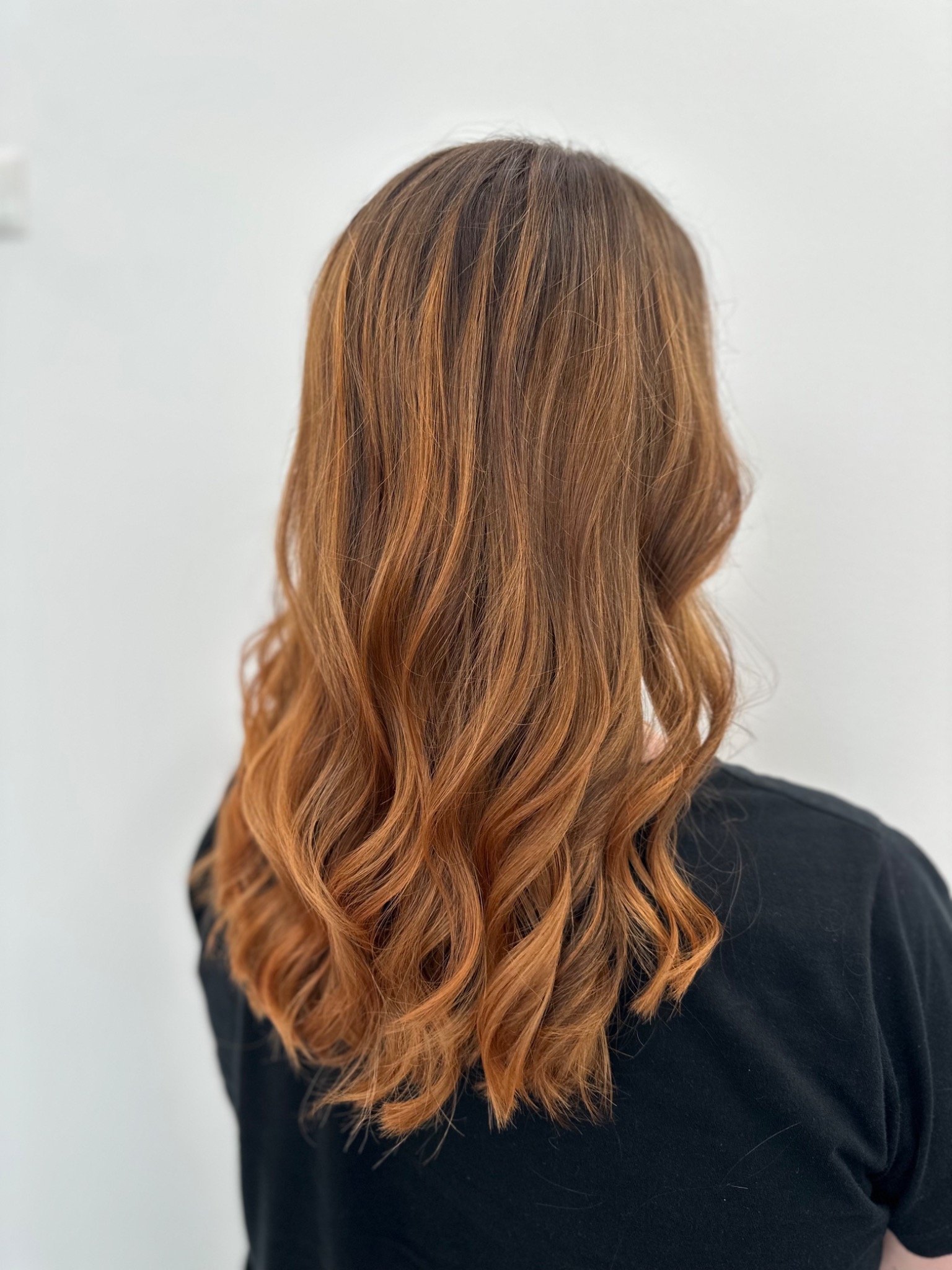 Voluminöse Lockenpracht in Kupferblond – Rückansicht einer gestylten Frisur im Salon.